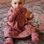 Baby girl wearing Lalaby Anna baby dress in Berry besty pink liberty organic cotton