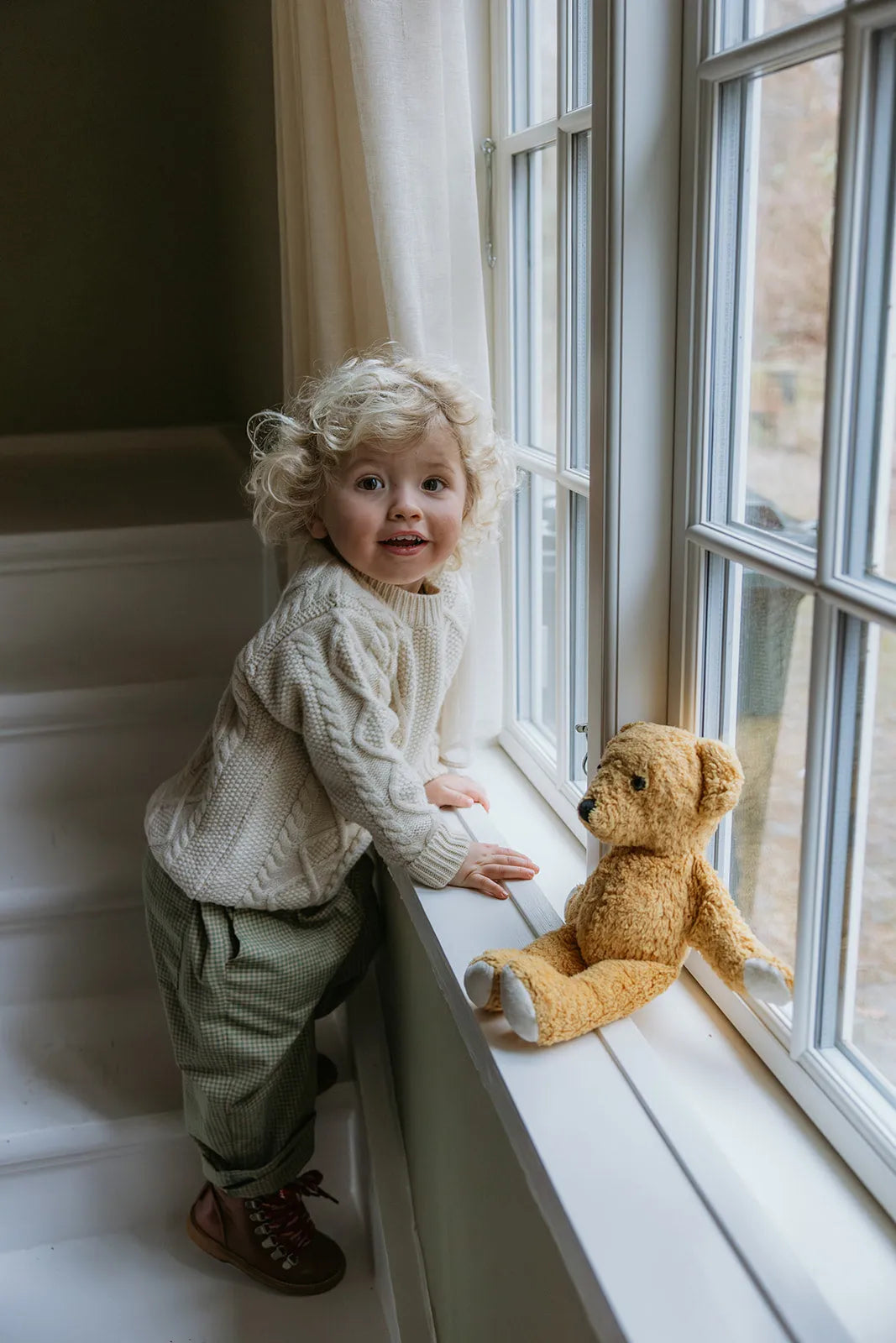 Boy wearing Lalaby Aran sweater for kids in natural white merino wool