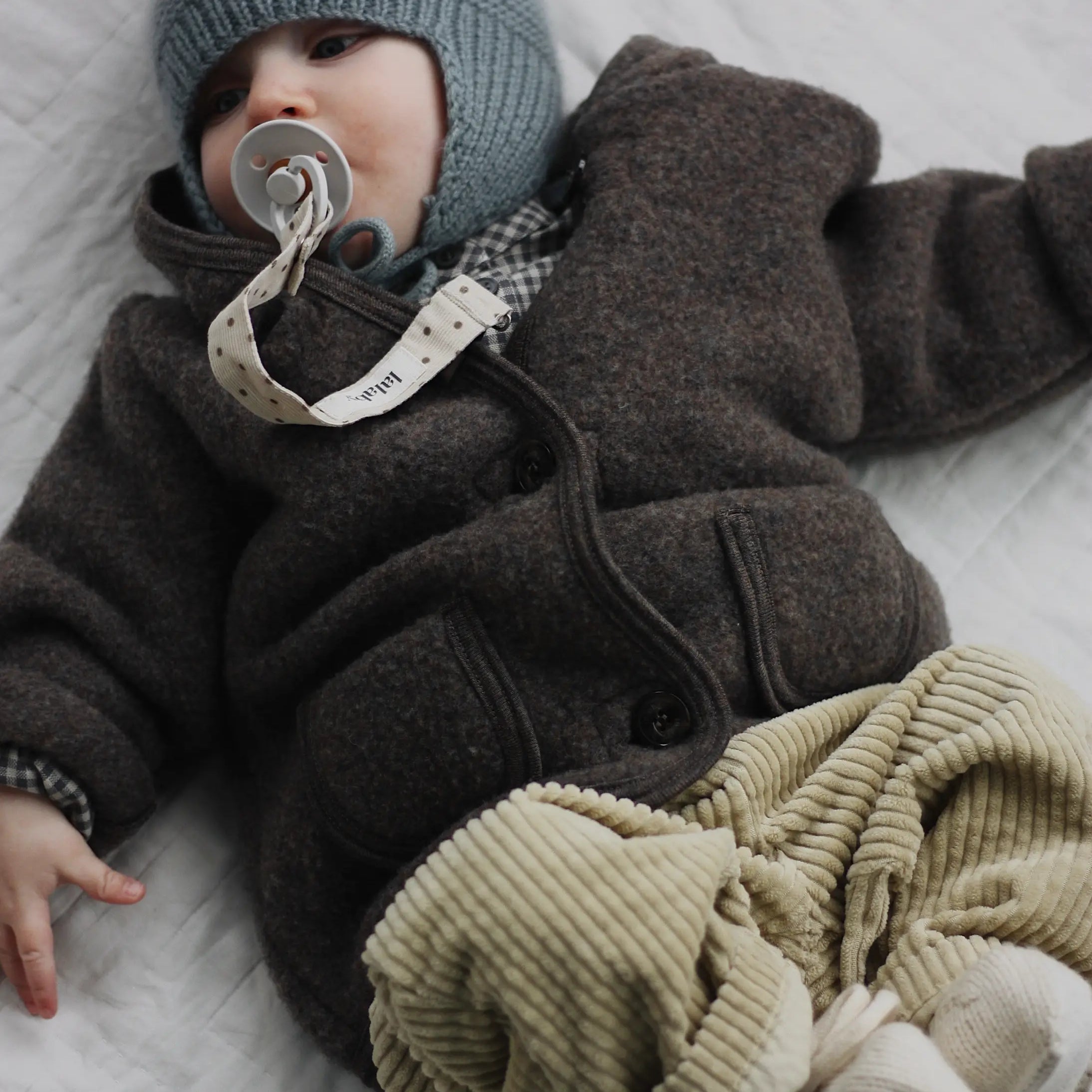 Baby boy wearing Lalaby Babar jacket for babies in chocolate brown merino wool