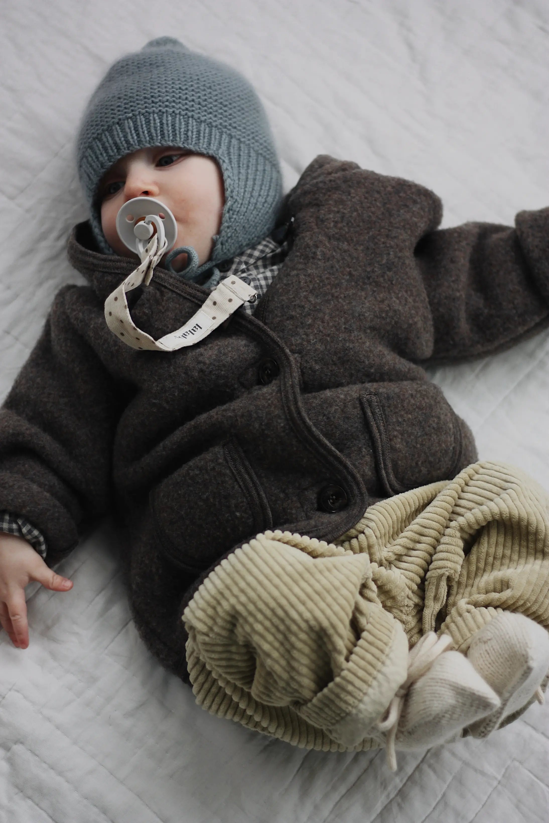 Baby boy wearing Lalaby Babar jacket for babies in chocolate brown merino wool