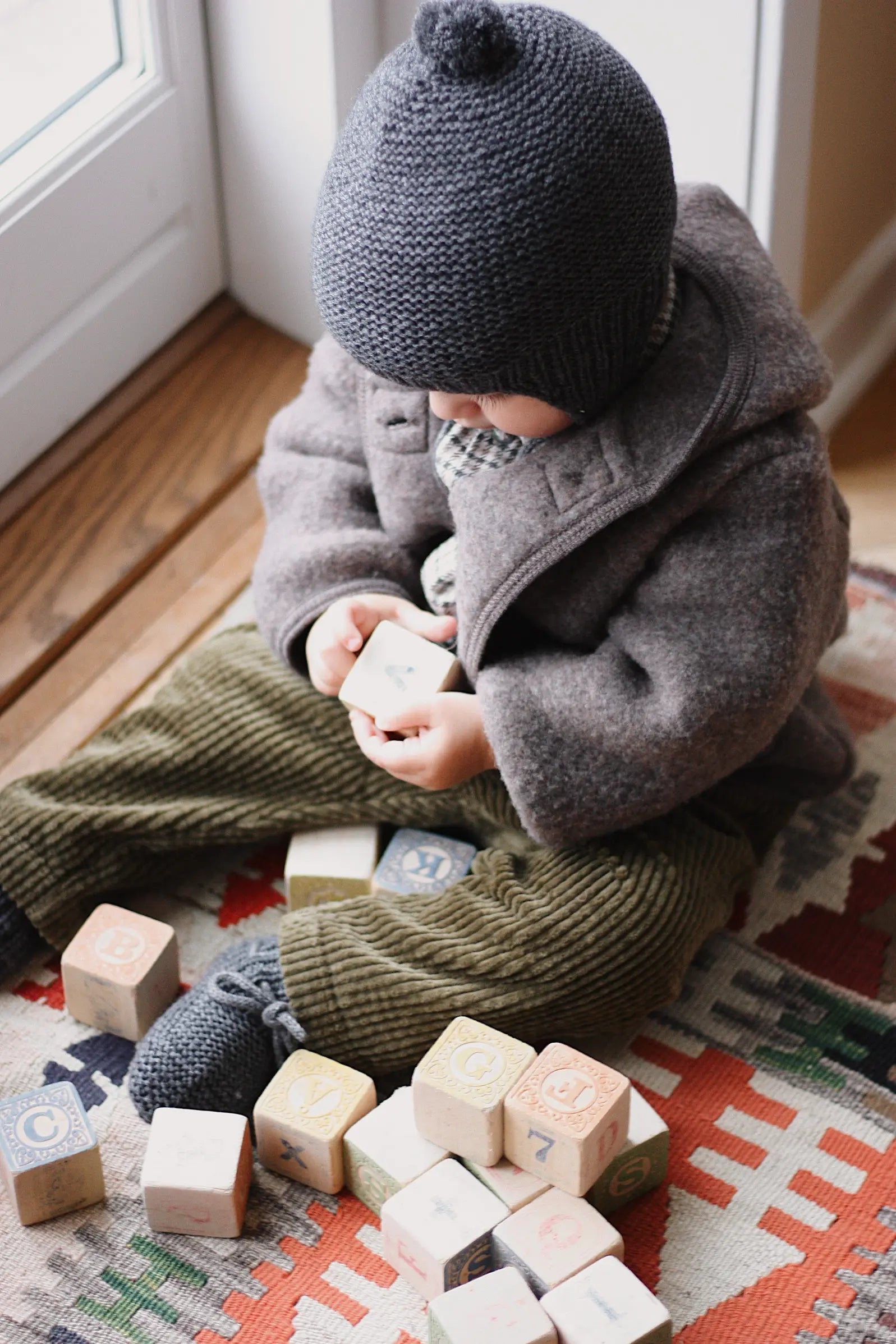 Baby boy wearing Lalaby Babar baby jacket in chocolate brown merino wool