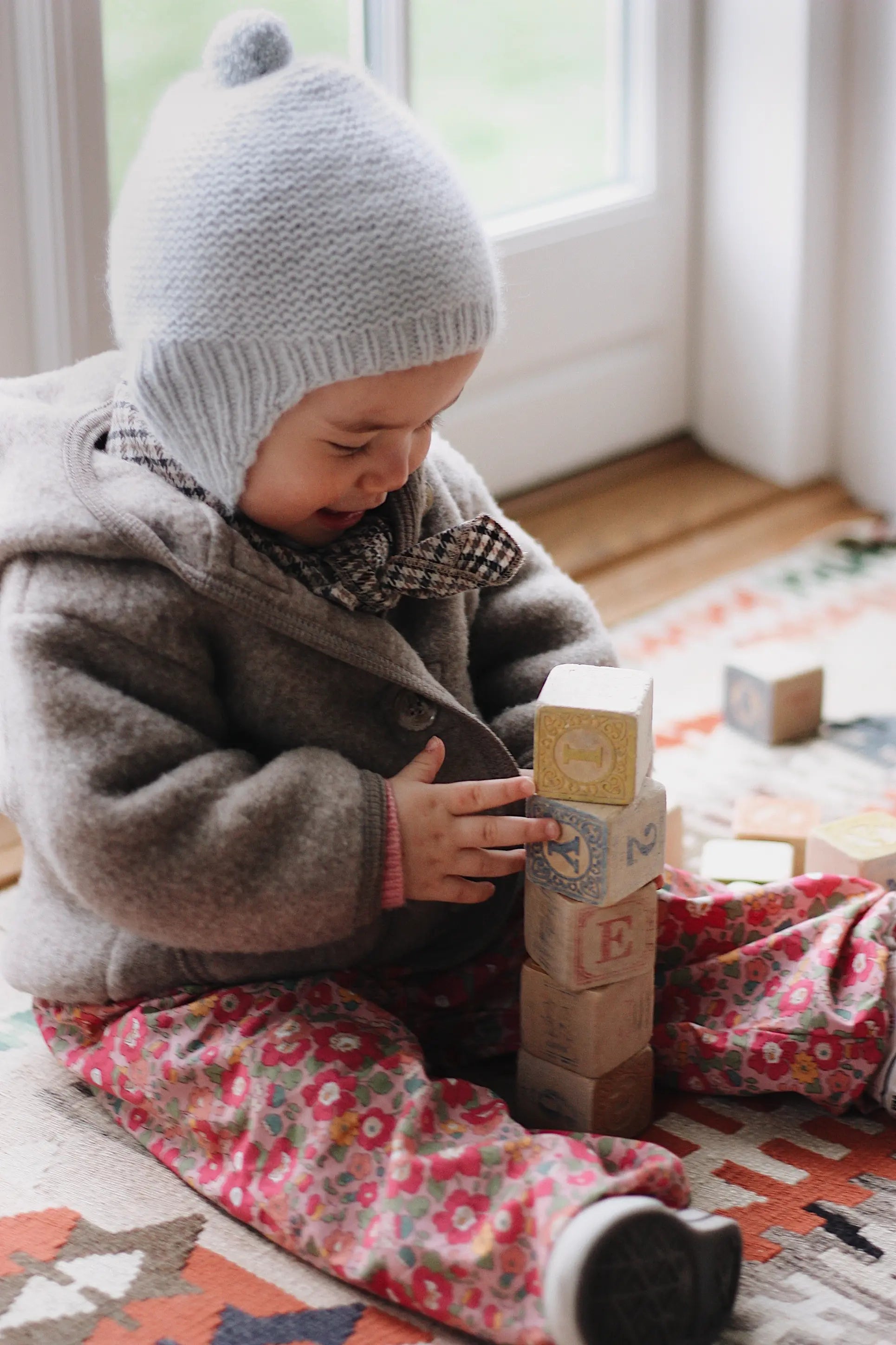 Baby girl wearing Lalaby Babar baby jacket in hazel brown merino wool