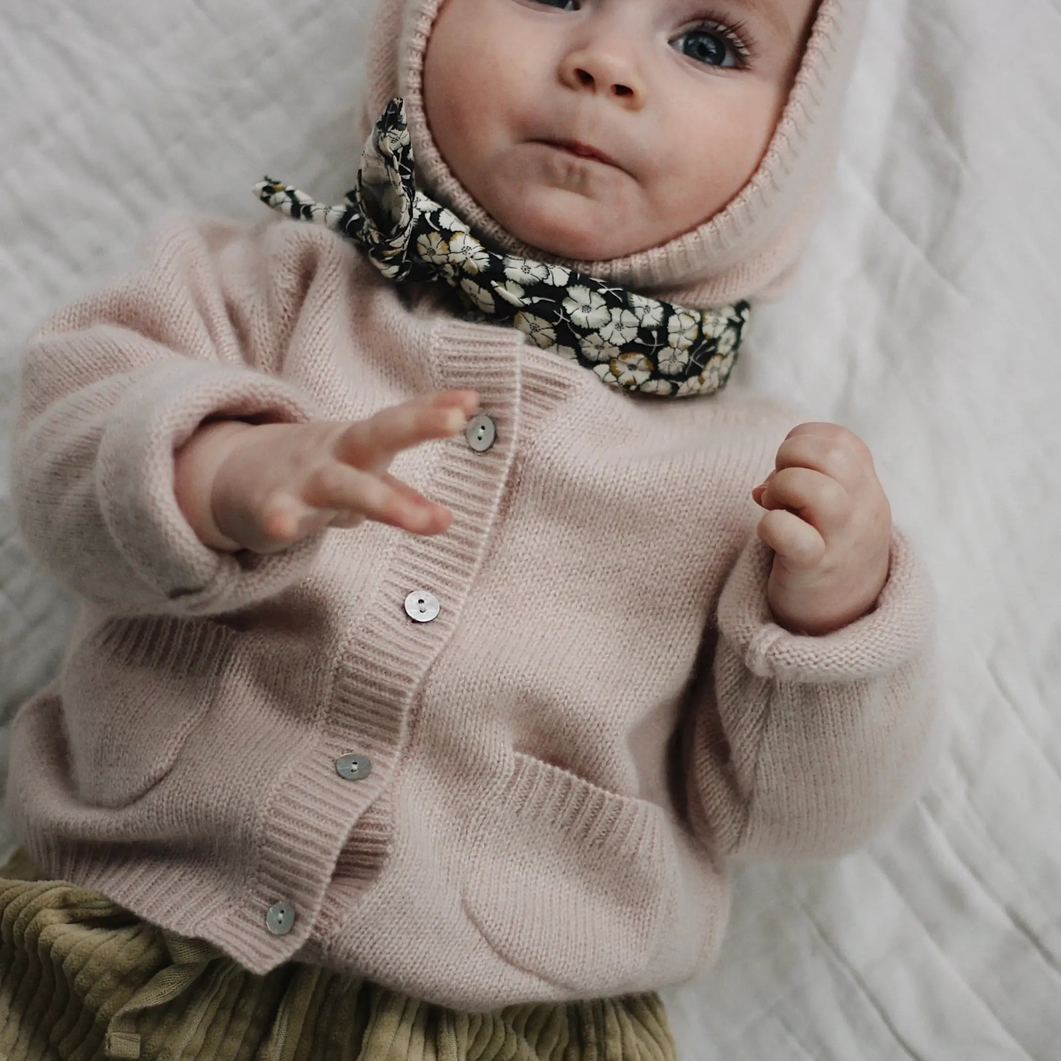 Baby wearing Lalaby Bobbie cardigan in powder pink cashmere