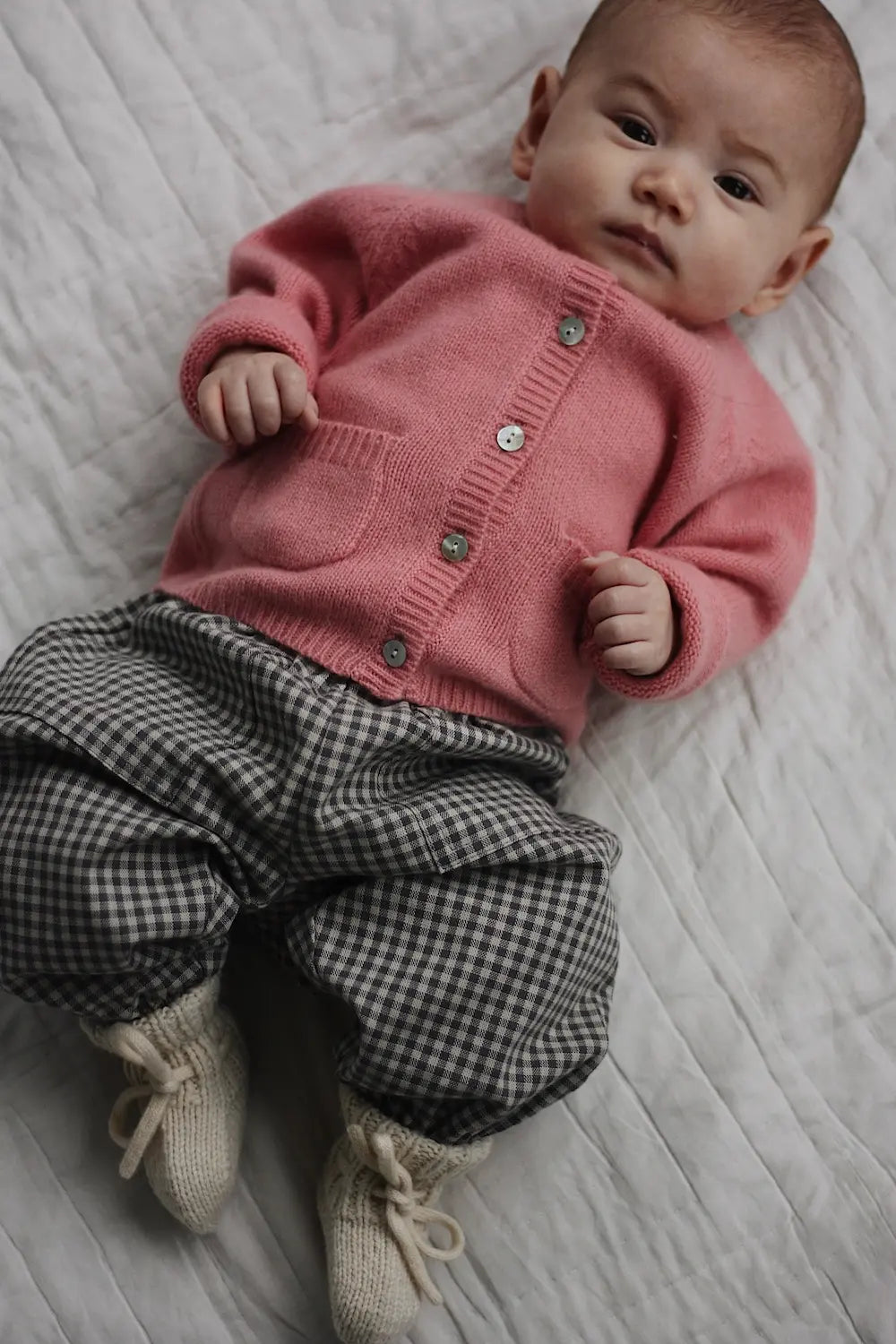Baby wearing Lalaby Bobbie cardigan in sorbet pink cashmere