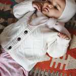 Baby girl wearing Lalaby Coby baby cardigan in natural white merino wool