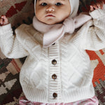 Baby girl wearing Lalaby Coby baby cardigan in natural white merino wool