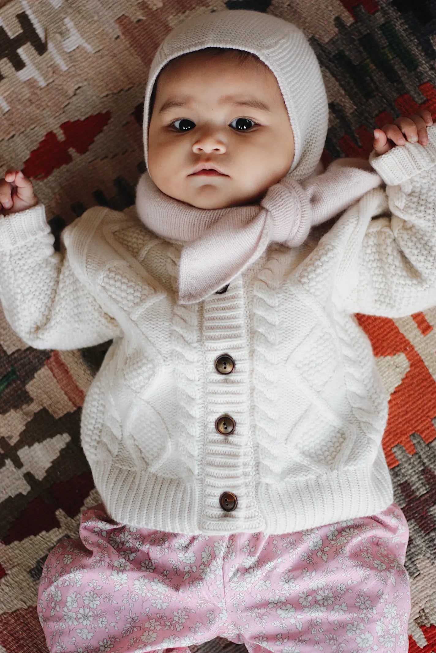 Baby girl wearing Lalaby Coby baby cardigan in natural white merino wool