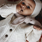 Baby girl wearing Lalaby Coby baby cardigan in natural white merino wool