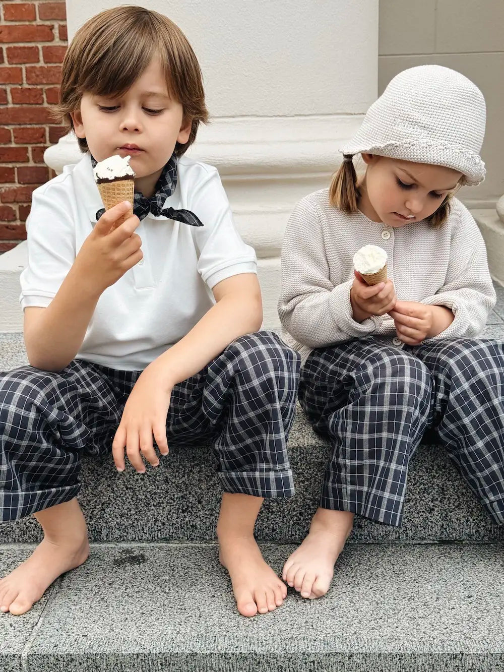 Boy and girl wearing Lalaby Frankie pants for kids in blue check organic cotton, eating ice cream