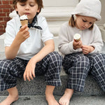 Boy and girl wearing Lalaby Frankie pants for kids in blue check organic cotton, eating ice cream