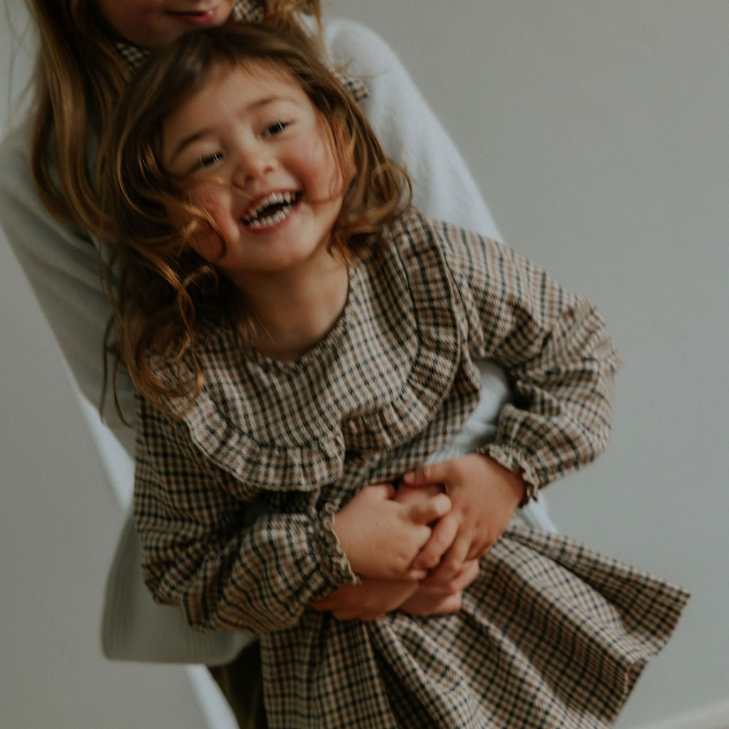Girl wearing Lalaby Noey dress for kids in tweedy check organic cotton