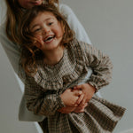 Girl wearing Lalaby Noey dress for kids in tweedy check organic cotton