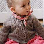 Baby girl wearing Lalaby Nomi baby cardigan in a millet brown baby wool, yak and cashmere blend