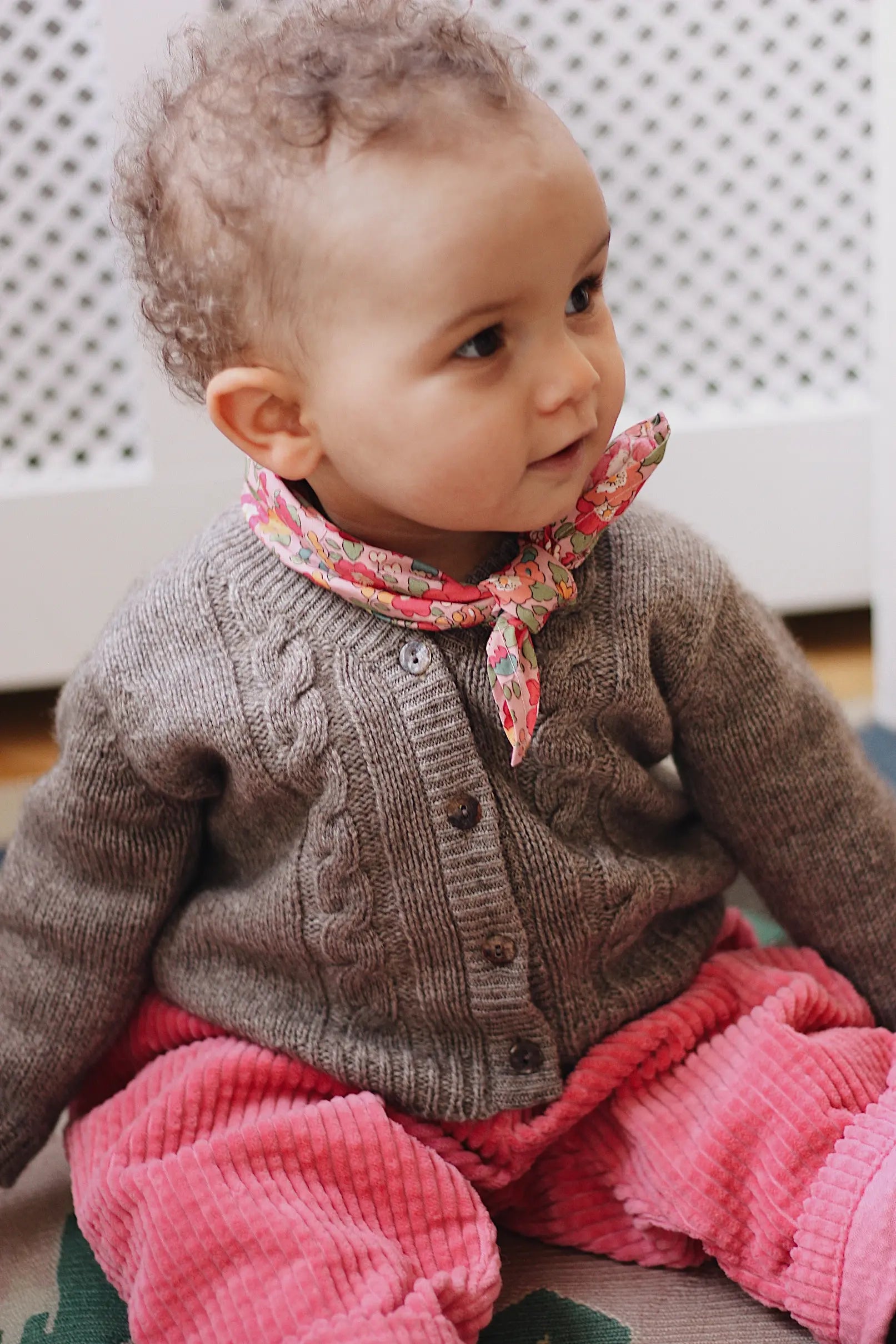 Baby girl wearing Lalaby Nomi baby cardigan in a millet brown baby wool, yak and cashmere blend