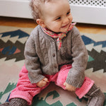 Baby girl wearing Lalaby Nomi baby cardigan in a millet brown baby wool, yak and cashmere blend