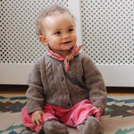 Baby girl wearing Lalaby Nomi baby cardigan in a millet brown baby wool, yak and cashmere blend