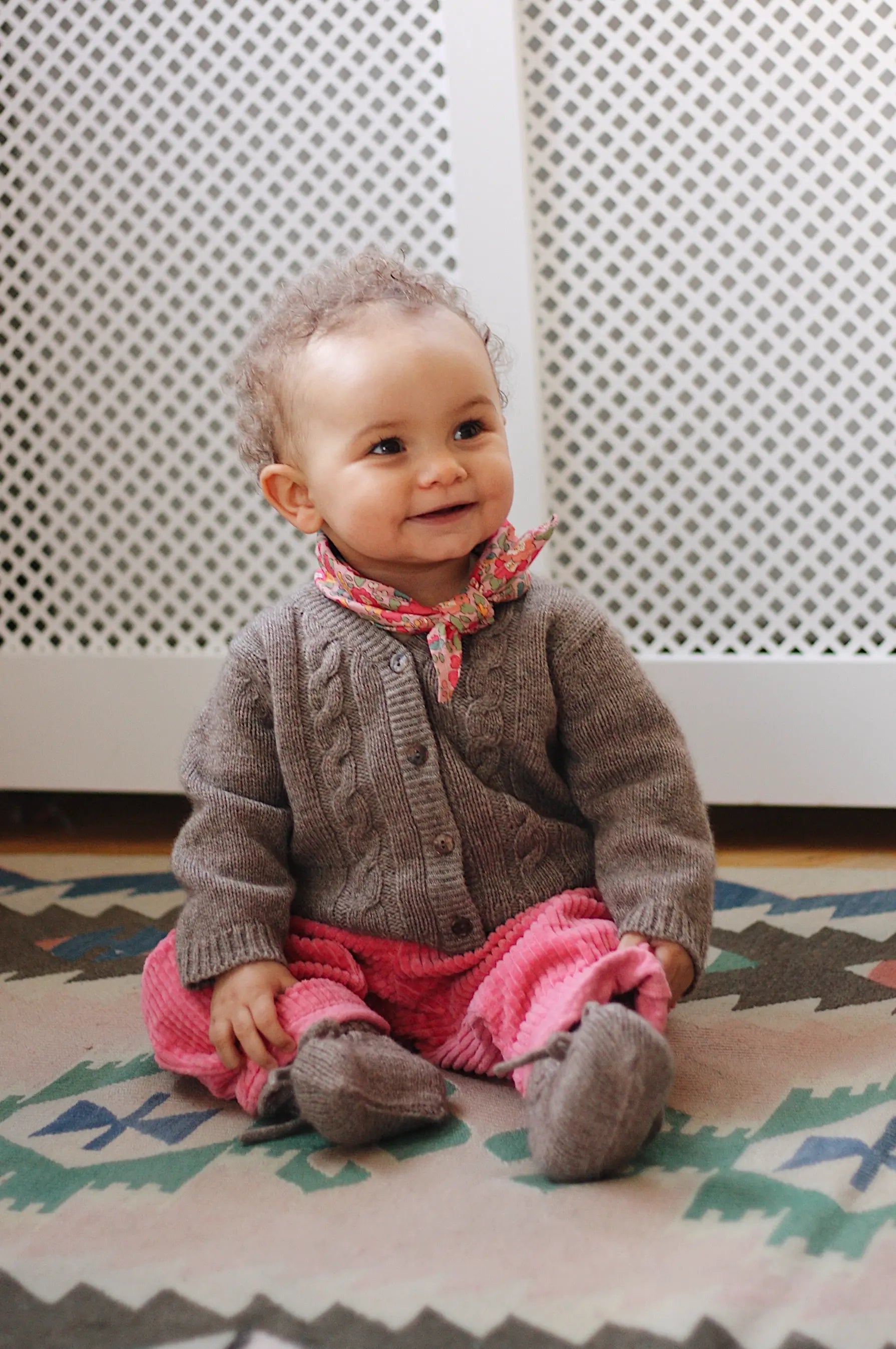 Baby girl wearing Lalaby Nomi baby cardigan in a millet brown baby wool, yak and cashmere blend