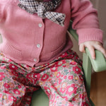 Baby girl wearing Lalaby Pixi baby pants in Berry besty pink liberty organic cotton