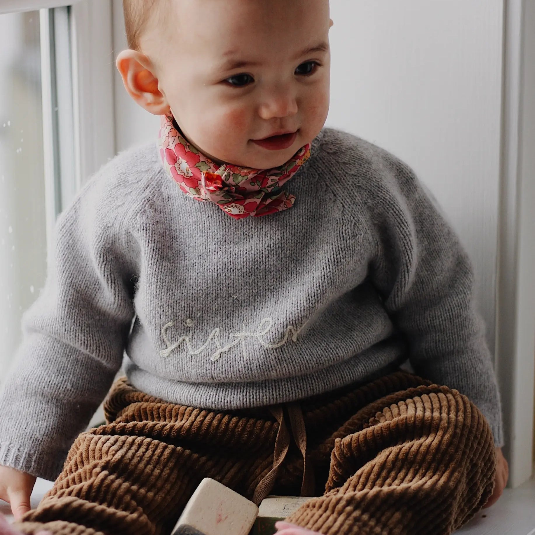 Baby girl wearing Lalaby Sister sweater for babies in a grey baby wool, yak and cashnere blend