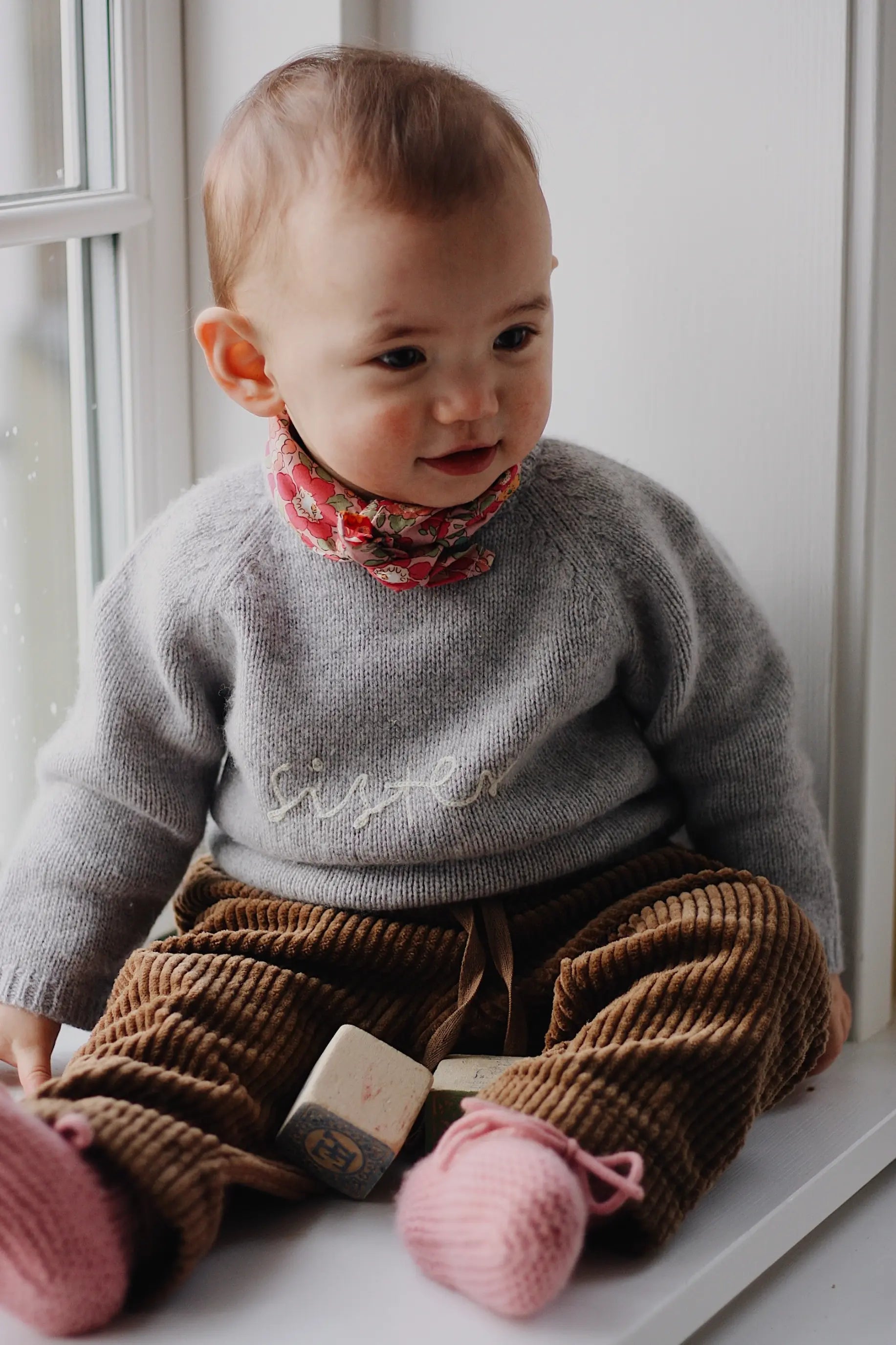 Baby girl wearing Lalaby Sister sweater for babies in a grey baby wool, yak and cashnere blend