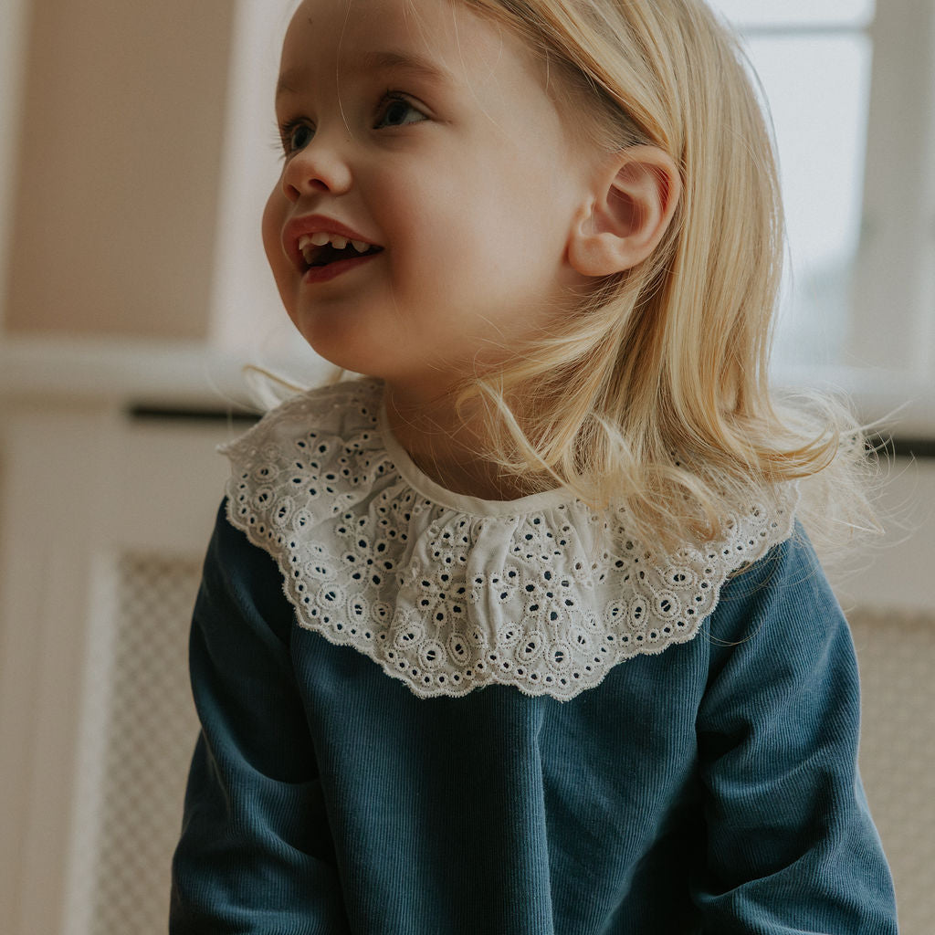 Girl wearing Lalaby Thea kids top in whale blue cotton baby cord