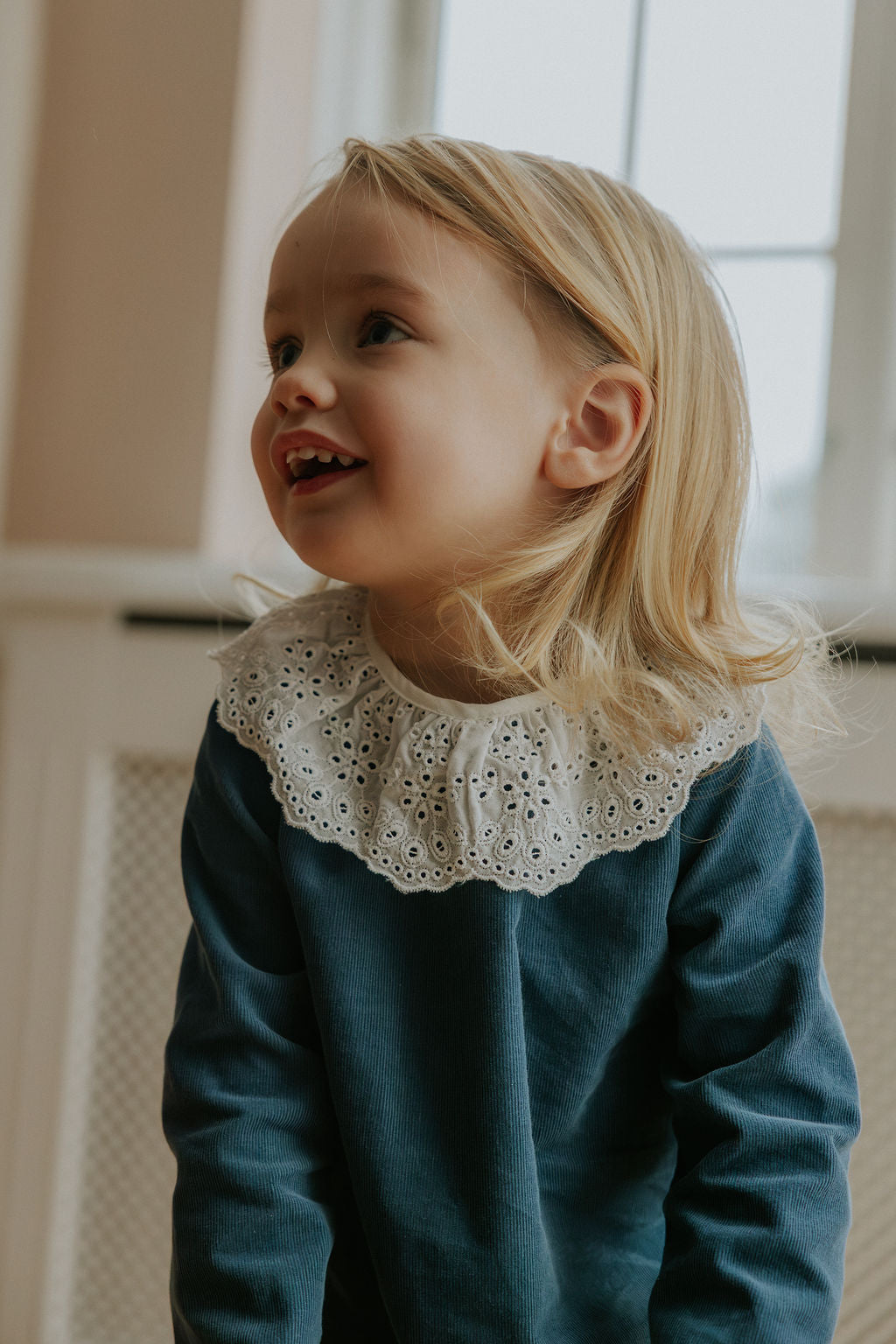 Girl wearing Lalaby Thea kids top in whale blue cotton baby cord