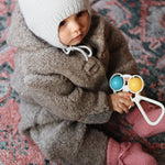Baby girl wearing Lalaby Thule baby onesie in grizzly brown merino wool