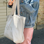 Woman holding a Lalaby Toto tote bag in a natural beige color, made from organic cotton, for everyday use