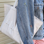 Woman holding a Lalaby Toto tote bag in a natural beige color, made from organic cotton, for everyday use